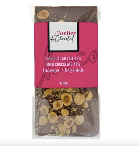 Packaged milk chocolate bar with hazelnuts and 'L'Atelier du Chocolat' branding on a white background.