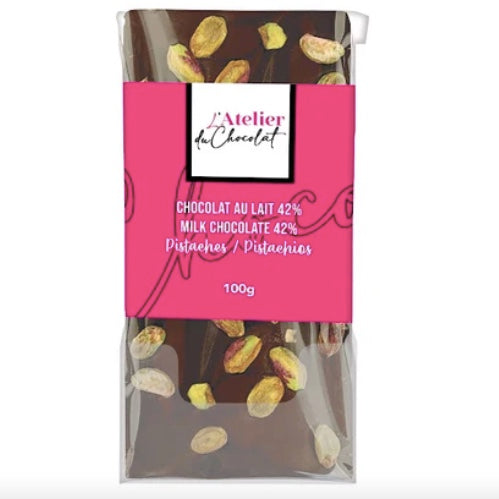 Milk chocolate bar with pistachios packaging featuring pink label and 'L'Atelier du Chocolat' branding.